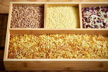 different, colorful types of groats in a wooden square box