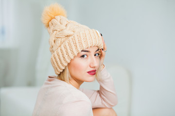 Beautiful lady in big white knitted hat indoors