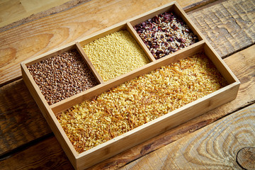 different, colorful types of groats in a wooden square box