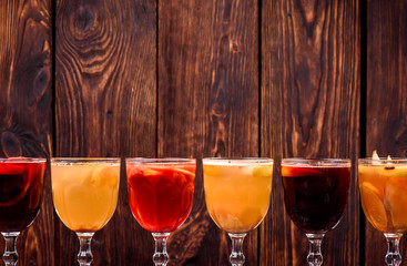 Assorted mulled wine. Variety of mulled wine in beautiful glasses standing in a row on a dark wooden background. advertising photo of mulled wine. Close up