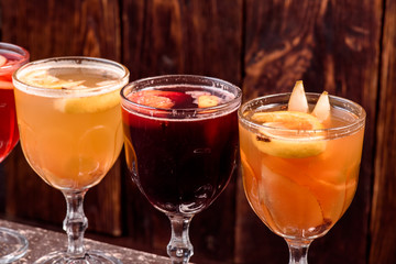 Assorted mulled wine. Variety of mulled wine in beautiful glasses standing in a row on a dark wooden background. advertising photo of mulled wine. Close up