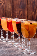 Assorted mulled wine. Variety of mulled wine in beautiful glasses standing in a row on a dark wooden background. advertising photo of mulled wine. Close up