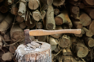 Ax stuck in a large wooden stump after work on the preparation of firewood.