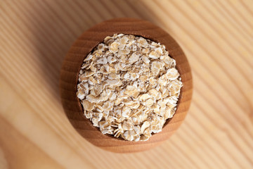 Oat flakes in a wooden bowl on the wooden table