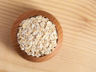 Oat flakes in a wooden bowl on the wooden table