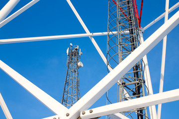metal structures of cell tower against a blue sky. ladder, support towers and metal construction of telecommunications tower 