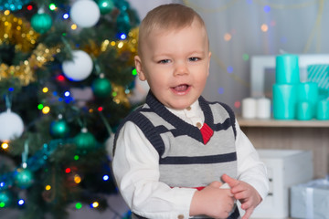 Naklejka premium Baby boy on Christmas near Christmas Tree among the gifts and decorations
