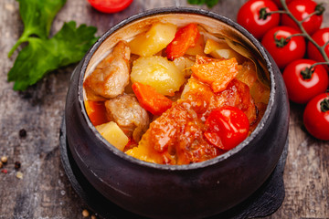 Crock pot pork roast with vegetables and cheese on wooden rustic table. Close up