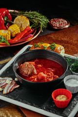 Homemade Russian, Ukrainian and Polish national soup - red borsch made of beetrot, vegetables and meat with sour cream in a black plate on a copper background. close up