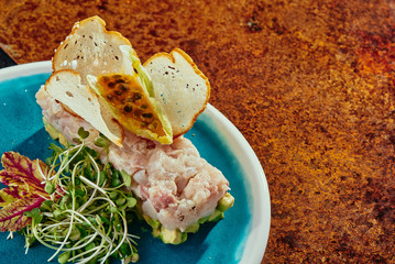 Delicious salmon tartare with toasted bread and salad on a blue plate and grilled vegetables on a copper plate on a copper background. Healthy lunch meal made of raw salmon. Classical French cuisine.