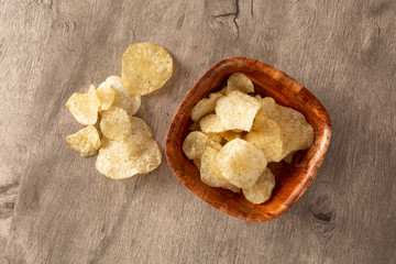 Potato chips on a bowl over wood background