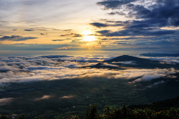 Beautiful nature landscape the sun is above the sea fog that covers the mountains and bright sky during sunrise in the winter at viewpoint of Phu Ruea National Park, Loei province, Thailand.