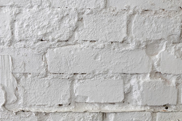 White brick wall. An old brick wall painted with paint and supplemented with plaster. Light background.