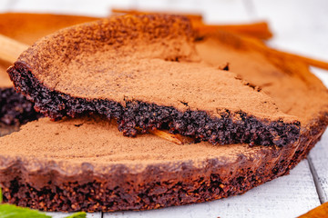 Sliced chocolate pie with cinnamon on wooden rustic table. Close up