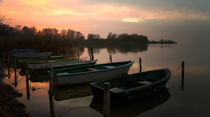 Fototapeta na wymiar rowboats on the lake shore after sunset, scenic landscape with copy space