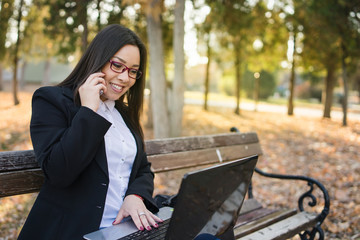 woman using laptop in the park on the bench