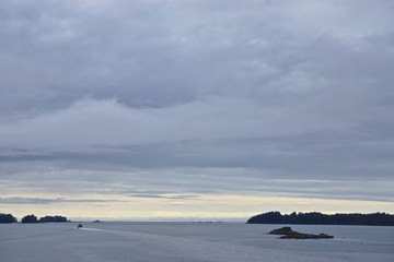 Sitka, Alaska, USA: Dawn on the horizon and thick clouds in the sky above the Eastern Channel, with islands and small boats in the distance.
