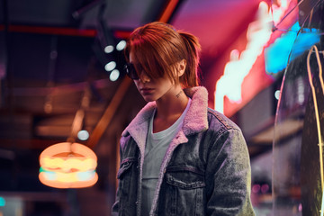 Stylish redhead girl standing in the night on the street.