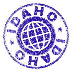 IDAHO stamp print with grunge texture. Blue vector rubber seal print of IDAHO label with scratched texture. Seal has words arranged by circle and globe symbol.