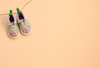 Baby sport shoes hanging on the clothesline on light background