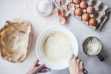 Process of making the dough, woman's hand whips eggs and flour in bowl Flat lay composition of ingredients and batter.selective focus