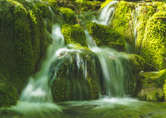 small waterfalls with green stones