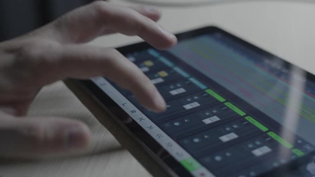 Producer musician checking mix levels on a software mixer on a tablet