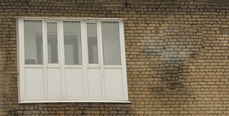 Glazed balcony. Glass balconies on the old brick building. Front view of a residential building in Russia.