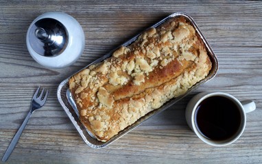 Cake, sugar dispenser and cup of coffee