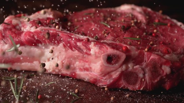 Camera follows putting herbs and spices on raw steak meat. Shot with high speed camera, phantom flex 4K. Slow Motion.