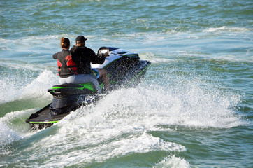 Young couple riding waves in tandem on a jet ski