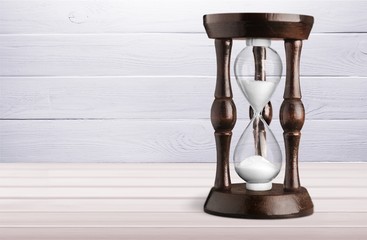 Sand running in hourglass on light background