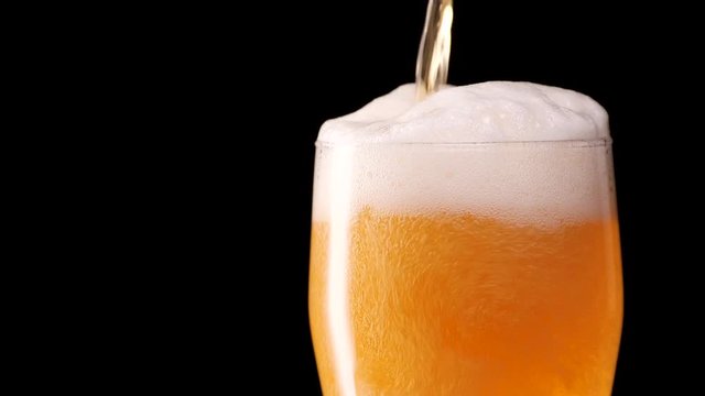 Light beer pouring in glass. With bubbles and foam.