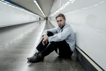 Sad young businessman jobless suffering from depression sitting depressed on ground street subway