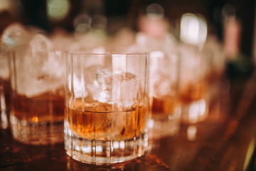A close up shot of whisky based cocktails with ice cubes on the bar. Fine alcohol, beverage and whisky concept.
