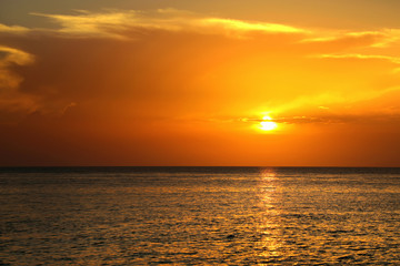 Colorful empty seascape with shiny sea over cloudy sky and sun during sunset in Cozumel, Mexico