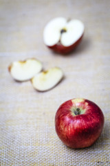 Big red apple next to slices of another apple.