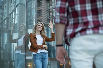 Fototapeta premium Waist-up portrait of hilarious young woman leaning against glass wall and looking at man