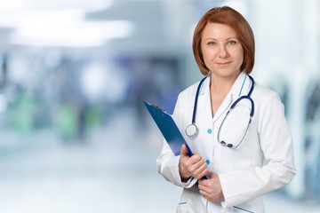Attractive young female doctor with blurred hospital interior on