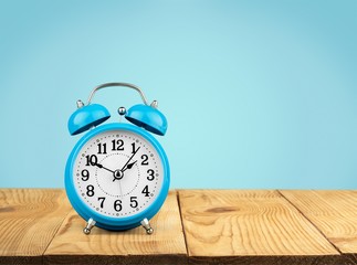 Blue retro alarm clock on wooden table on wall background