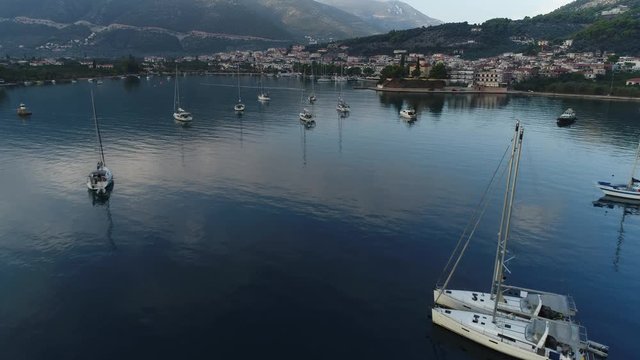 Aerial view. Flight at low altitude between the masts of sailing ships anchored in the bay near Epidavros embankment in the early morning.