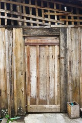 Rustic wooden door set in funky weathered wood wall near Luang Prabang, Laos