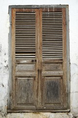 Weathered wooden door in a crumbling white plaster wall