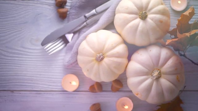 Thanksgiving holiday scene. Wooden table, decorated with pumpkins, autumn leaves and candles. Flatlay, Top view. 4K UHD video footage. 3840X2160 