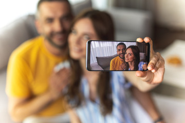 Beautiful happy man and woman using smartphone while staying at home
