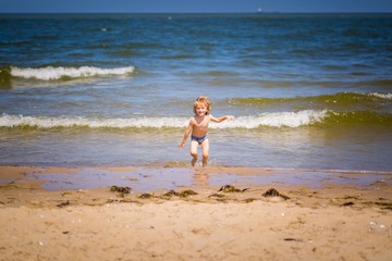 Young caucasian boy playing on sea shore at sunny summer