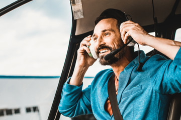 Close up of a happy young man wearing big headphones while sitting in the helicopter and smiling © Yakobchuk Olena
