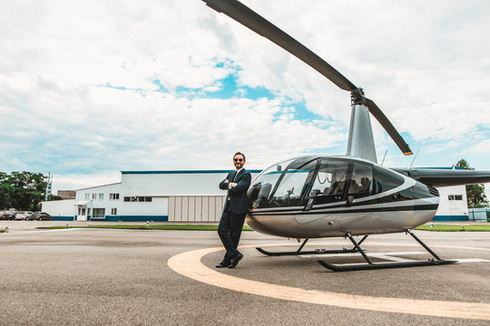 Happy emotional businessman smiling and looking glad while leaning on his helicopter