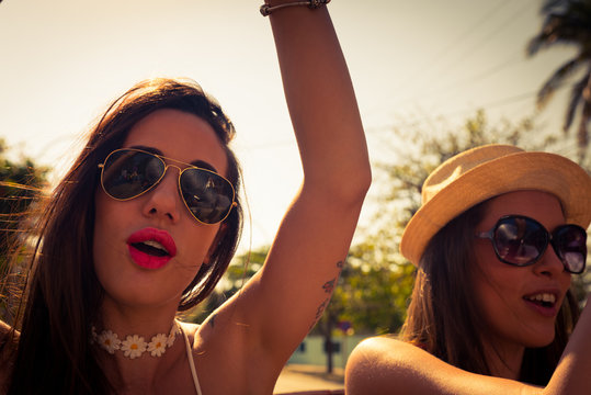 dos chicas sexys y bellas a contraluz con sombrero en un coche descapotable