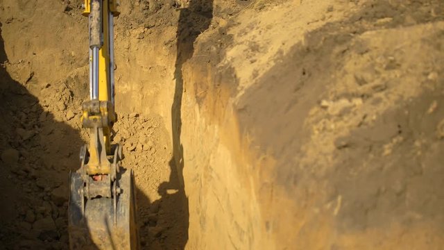 Excavator bucket tamps soil. Construction site. Excavator level the soil, new pipeline construction. View from trench excavator excavating ditch, digging a trench. Close-up. close up 4 K